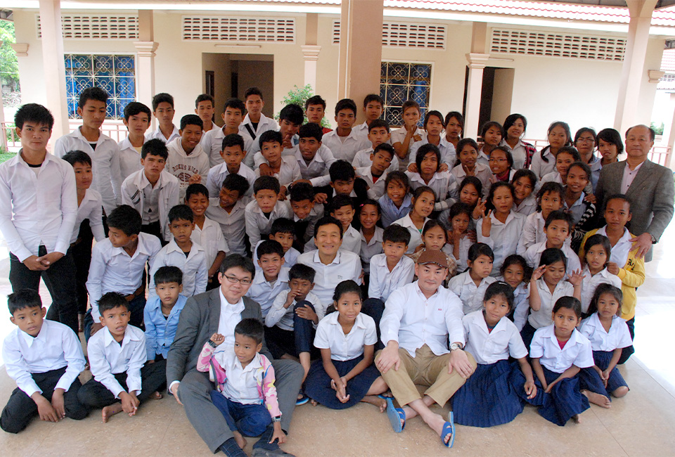 株式会社ディライトが支援する学校で笑顔の子どもたちと記念撮影をする葬儀支援スタッフ